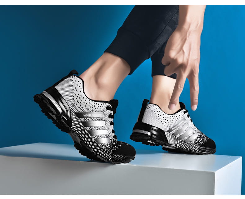 Chaussures de running pour hommes Covadis en maille respirante en noir et argent : elles présentent un matériau en maille et trois bandes parallèles sur le côté.