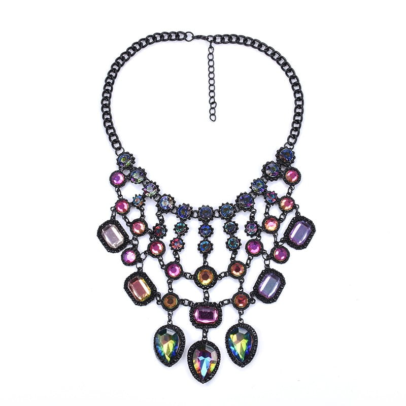 Un collier ras-du-cou bohème multicolore audacieux, avec une chaîne noire et des pierres précieuses irisées rose, violet, or et vert, serties dans des montures en métal foncé.