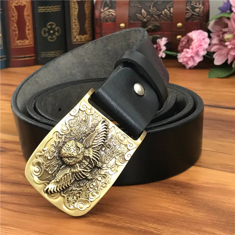 Black leather men’s jeans belt with a detailed gold-toned eagle buckle featuring ornate cloud and scrollwork designs.