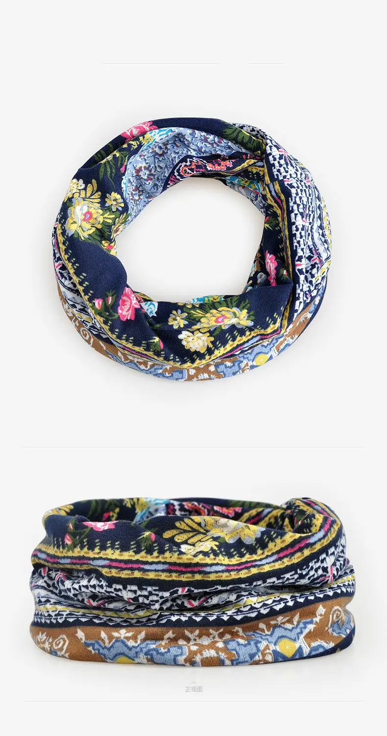 A navy blue infinity scarf with a vibrant floral and geometric pattern in shades of pink yellow gold and white as part of a floral knit beanie hat unisex casual autumn headwear collection.
