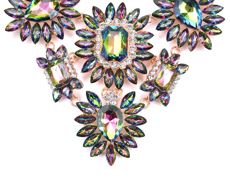 Un magnifique collier-sautoir en cristal à éclat irisé, avec des montures en métal à tons or rose et des cristaux facettés multicolores aux teintes d’arc-en-ciel, disposés en motifs floraux dans un style de ras-du-cou bohème.
