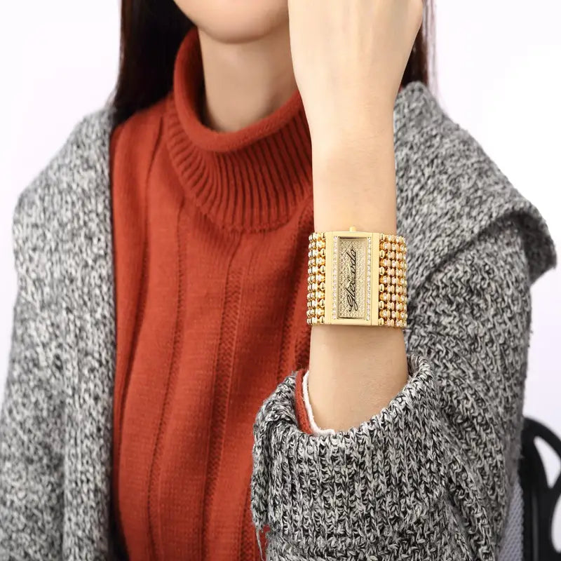 Gold quartz women watch with a gold-tone rectangular face, diamond-encrusted dial, and beaded bracelet.