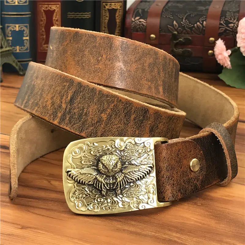 A rustic brown leather belt with an ornate brass owl buckle designed for men jeans.
