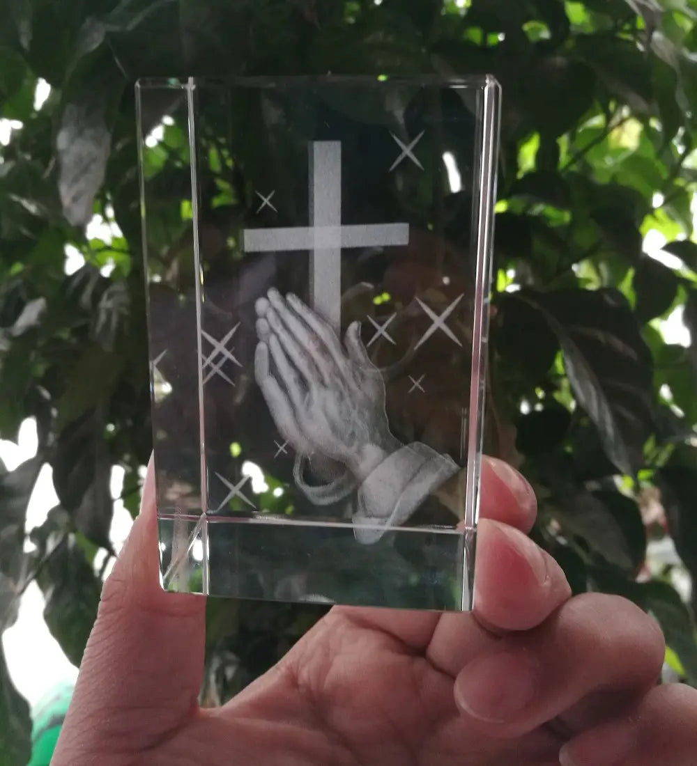 Statue de croix en cristal 3D transparente avec mains priantes, présentant une croix gravée et un motif de mains priantes, avec de subtils motifs d’éclats d’étoiles.