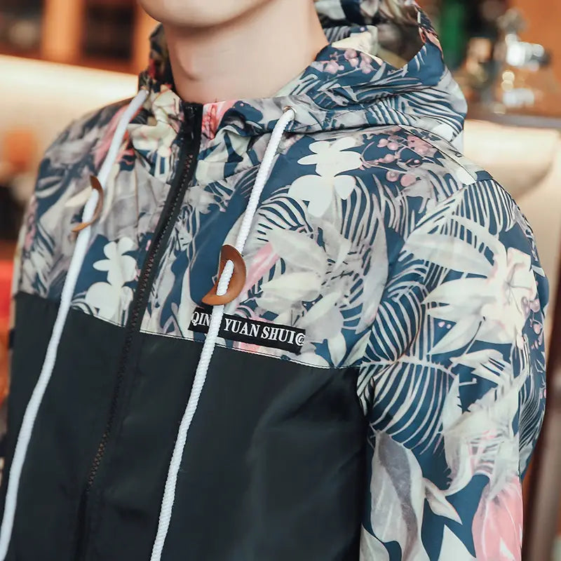 Mens hooded jacket in asia size featuring a navy and white tropical floral print with a black lower panel and a brown leather toggle on the drawstring, lightweight windbreaker design.