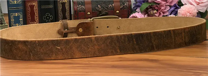 A rustic brown leather men’s jeans belt with a worn textured surface and brass owl buckle.