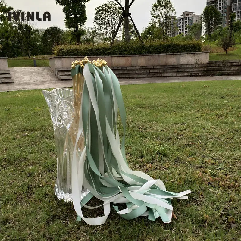 un bouquet délicat de baguettes ruban de mariage menthe et blanches, disposé avec élégance dans un vase en verre transparent présentant des motifs découpés complexes, présenté en lot de 50.