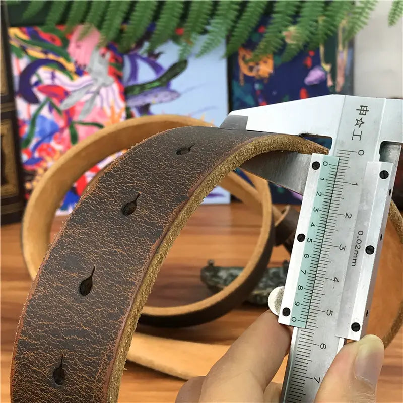 A brown distressed leather belt strap with evenly spaced punched holes for a genuine leather brass owl belt buckle designed for men jeans.