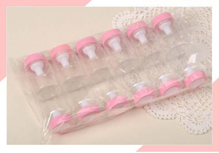 ピンクのねじ込み式キャップと白い乳首を備えた透明なプラスチック製ベビーボトル型。ベビーシャワーの引き菓子用ミニミルクボトルとして、透明なプラスチック製スリーブに梱包されています。