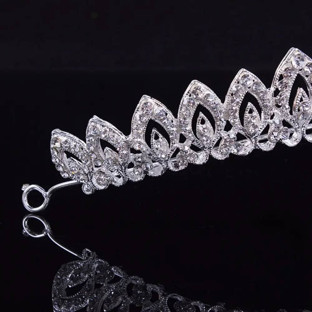 Una diadema de boda floral con tiara de novia de cristal plateado brillante, adornada con recortes intrincados con forma de hojas y cristales transparentes densamente colocados.