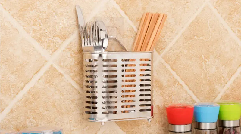 Silver stainless steel cutlery and utensil storage rack with a perforated design holding forks, knives, spoons, and wooden chopsticks.