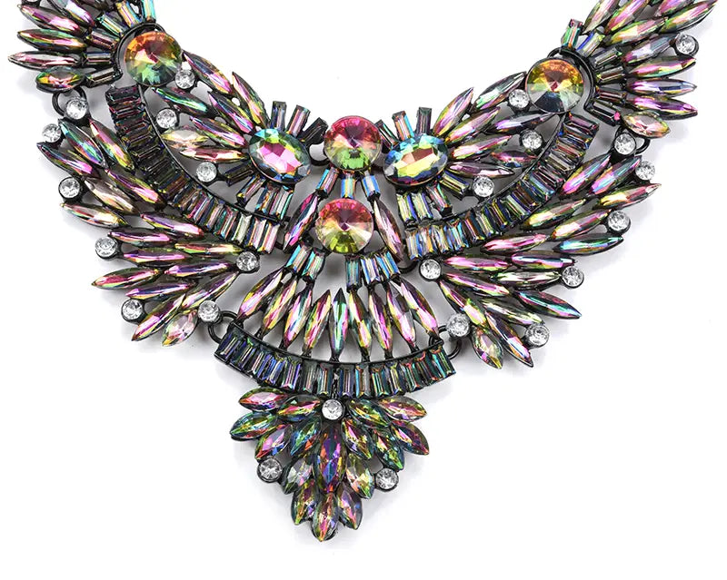 Un collier ras-du-cou en cristal d’affirmation bohème multicolore éblouissant, avec un design symétrique en forme d’aile, des cristaux irisés superposés et des accents en métal noir.