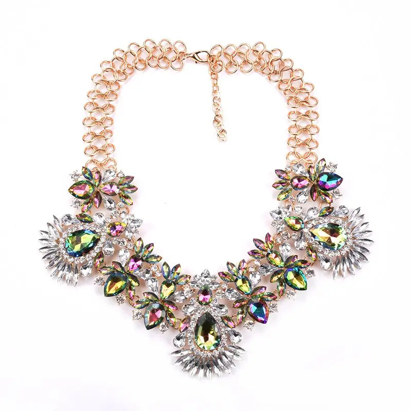Un collier ras-du-cou bohème multicolore éblouissant, avec une chaîne en or rose et une quincaillerie en métal aux tons d’argent, comprenant des cristaux en forme de goutte et de feuille irisés.
