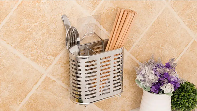 Silver stainless steel wall-mounted utensil holder with a perforated design holding forks knives and wooden chopsticks for stainless steel cutlery and utensil storage rack.