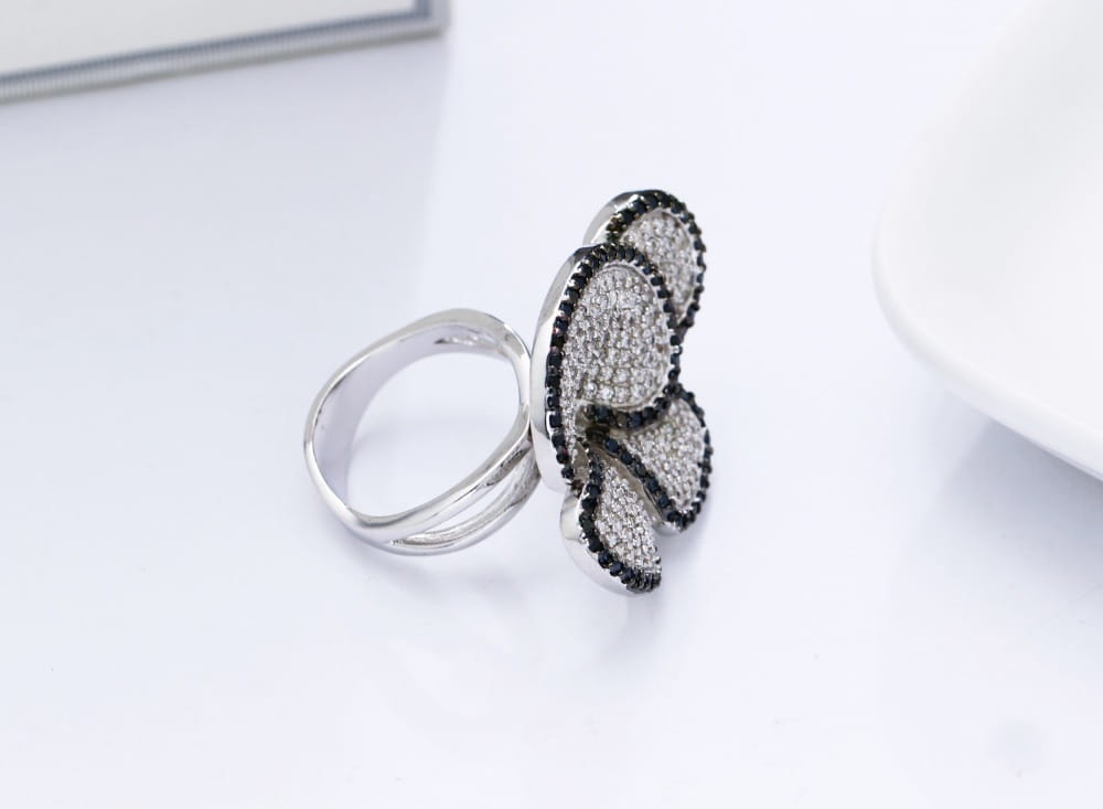 Silver butterfly ring adorned with pave-set black and clear crystals featuring a black and white crystal statement flower design.