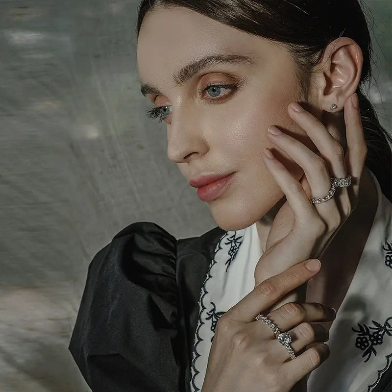 Une femme portant un chemisier brodé noir et blanc à manches bouffantes, modélisant une bague d’éternité cœur en argent sterling.