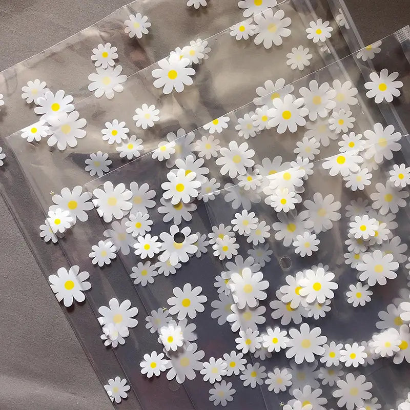 Blumige, durchsichtige Reisekosmetiktasche aus durchsichtigem Kunststoff, verziert mit weißen Gänseblümchen mit gelben Zentren.