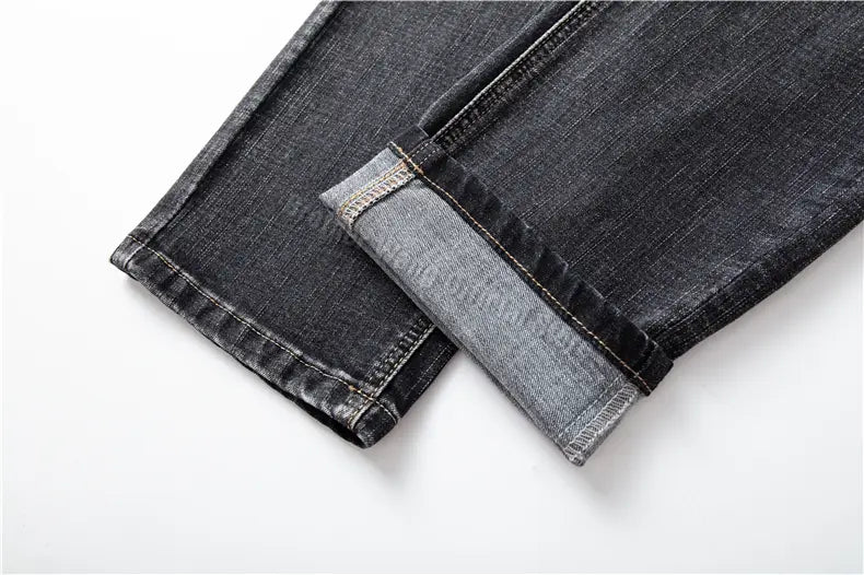 Jeans en denim stretch pour hommes, coupe regular fit, en denim foncé, avec un revers retroussé laissant apparaître un tissu intérieur plus clair.