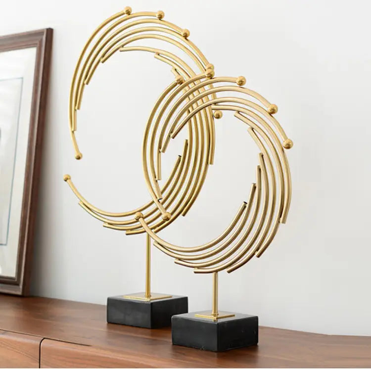 Gold metal abstract sculpture with interlocking circular rings and small spherical accents mounted on black square bases designed as office desk decor.