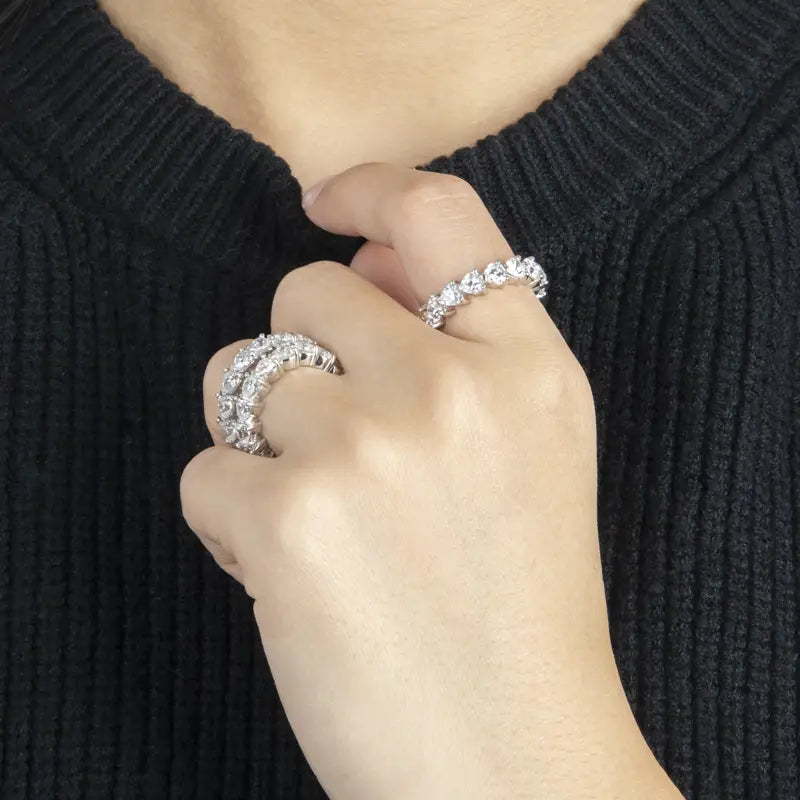 Une bague d’éternité cœur en argent sterling, dotée d’une bande d’éternité en diamant étincelante, dans un sertissage argenté élégant, avec des modèles à une rangée et à double rangée de pierres.