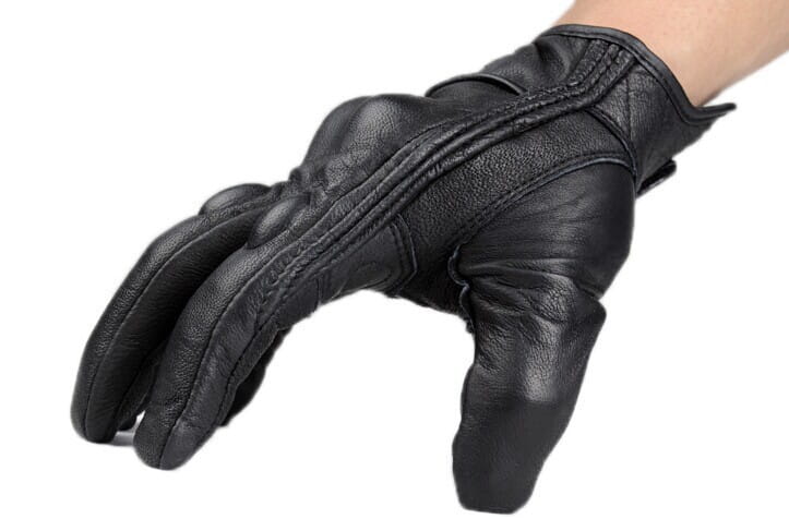 Guante de motocicleta de cuero negro con costuras reforzadas y nudillos de carbono acolchados mostrados desde el lado posterior para protección del equipamiento de conducción.