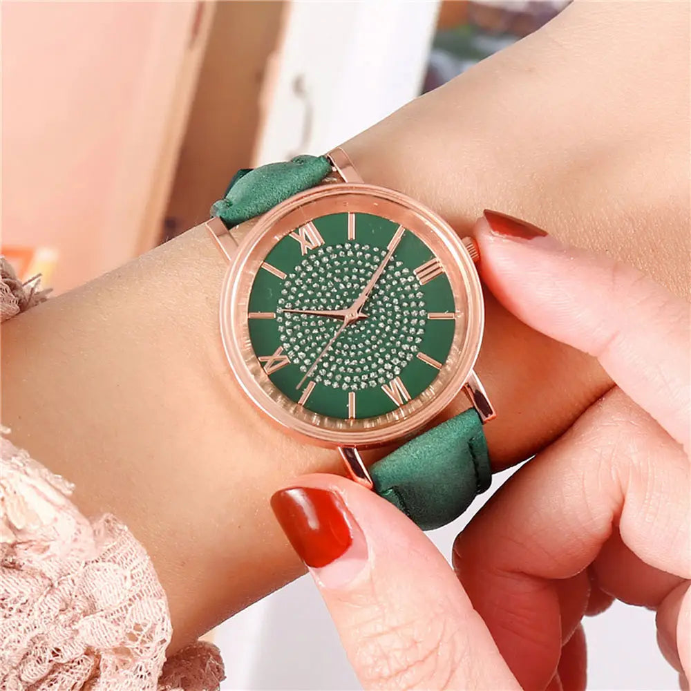 Rose gold crystal quartz women watch with a green dial decorated with sparkling rhinestones and roman numerals, paired with a matching green suede leather strap.