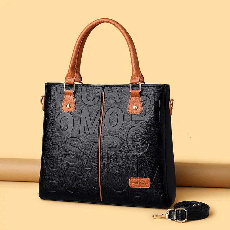 Black crossbody handbag in pu leather with black embossed lettering and tan handles designed in style1 style2 style1.