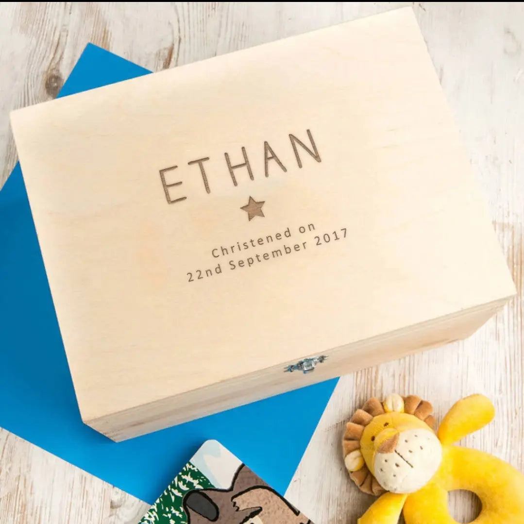 木製の淡色の、個別に名入れした洗礼記念品保管箱。刻印された名「Ethan」と洗礼日が入っており、文字の下には小さな星のデザインを施しています。