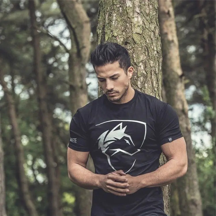 T-shirt d’entraînement en coton noir à manches courtes pour homme, avec logo de tête de loup stylisée blanche sur la poitrine et marque Malete sur la manche gauche, conçu pour le streetwear masculin.