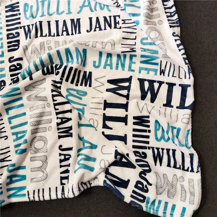 Eine weiche weiße, personalisierte Baby-Wickeldecke aus Fleece mit einem verspielten, sich wiederholenden Muster der Namen William und Jane in kräftigen blau-dunkelblauen und grauen Schriftarten.