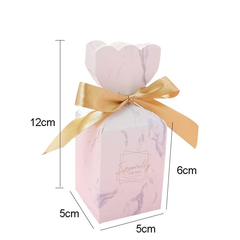 Eine zarte Hochzeits-Gastgeschenkbox aus rosafarbenem, marmoriertem Blumendesign mit gewellter Oberkante, gebunden mit einer goldfarbenen Schleife