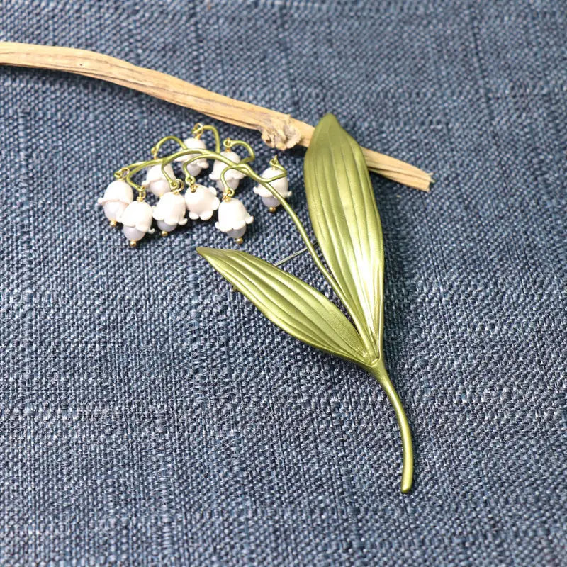 小さな白いエナメルの花と、精細な葉脈を施した、繊細なブランジ色（銅合金のような色調）のデザインの鈴蘭の真珠のブローチピン。