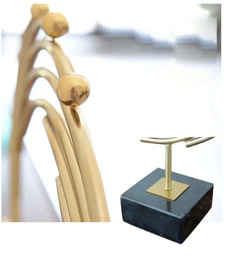 gold-toned metal hairbrush with spherical decorative knobs and a sleek curved handle designed as an abstract sculpture for office desk decor.
