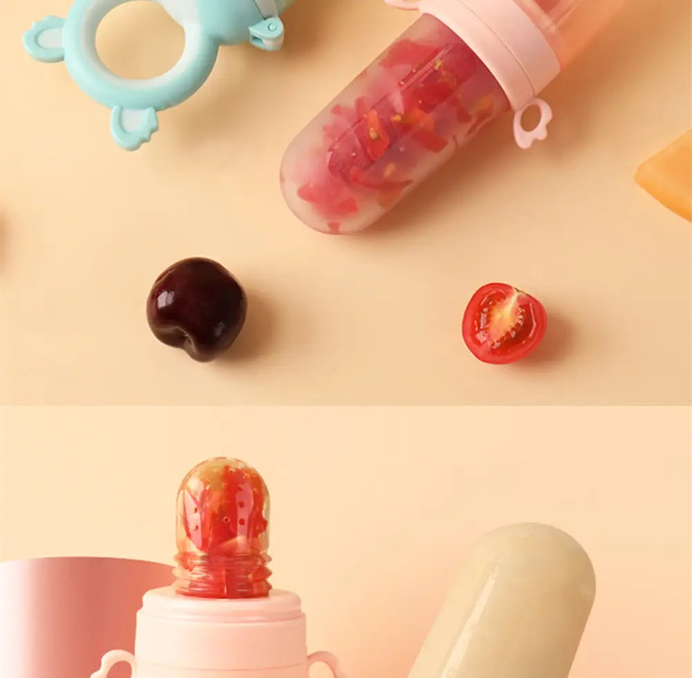 Rosa Silikon-Babysqueeze-Feedingflasche und Löffelspender mit einer klaren, abgerundeten Oberseite, gefüllt mit roten Fruchtstücken, ausgelegt für sicheres Füttern von Säuglingen.