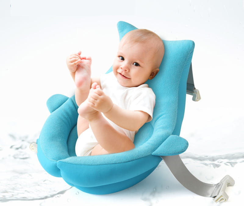 Blue plush dolphin-shaped baby bath seat with gray safety straps designed as a foldable newborn bath mat and cushion