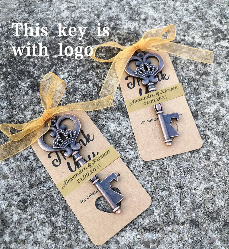 Encantos de llaves antiguos estilo plata con detalles de corona, atados a etiquetas de cartón beige con cinta dorada para recuerdos abridores de botellas para bodas personalizados.