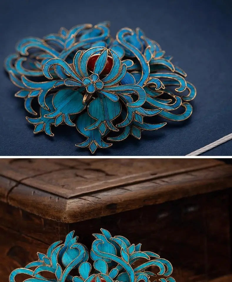 A delicate turquoise enamel filigree brooch featuring floral design with gold-toned metalwork and a central red gemstone from Palace Jewelry.