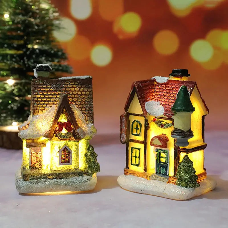 Deux maisons de village de Noël à LED éclairées, avec des veilleuses à batterie, présentant un toit en tuiles brunes et un toit en tuiles rouges avec des détails blanchis par la neige et un éclairage intérieur chaud.