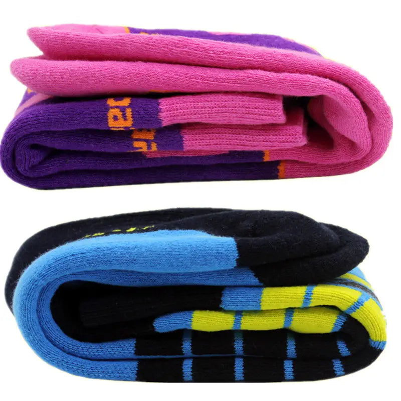 Une paire de chaussettes de ski colorées, comprenant une matière thermique en coton épais, avec des rayures rose vif et violet, et des motifs à carreaux noir, bleu et jaune audacieux, idéales pour les sports d’hiver.