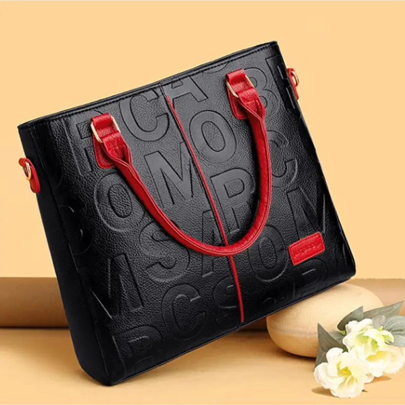 Black leather tote bag with embossed tomorrow lettering and red handles in style1 style2 style1 combines pu leather satchel design and crossbody functionality.