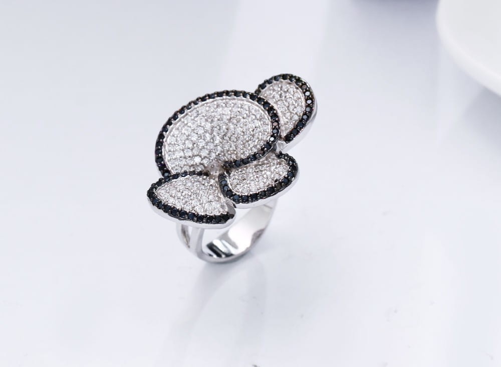 A silver black and white crystal statement flower ring featuring a bold three-leaf clover design with pavé-set white and black diamonds.