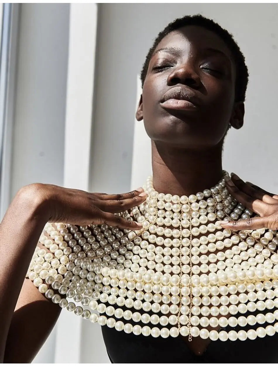 Un collier choker en perles à plusieurs rangées et superpositions, couleur blanc crème, conçu comme un collier de mode en chaîne corporelle de perles.