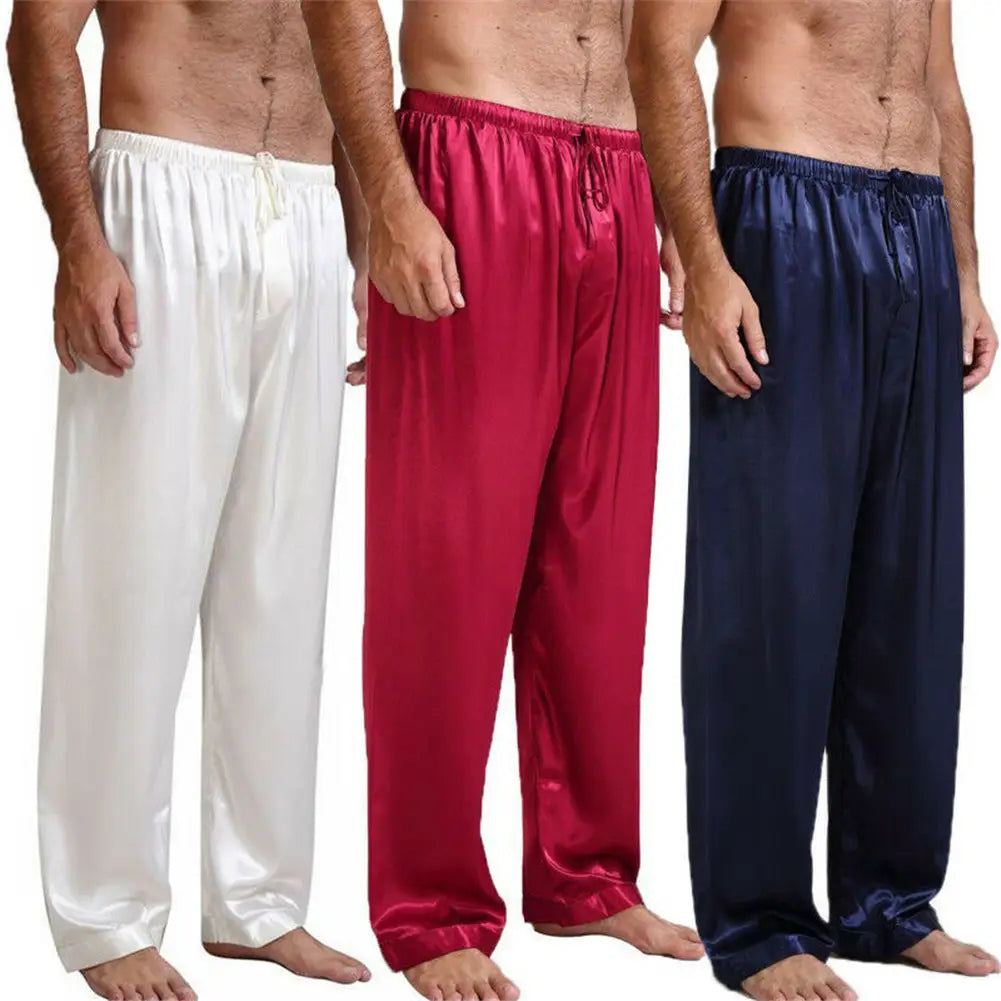 Trois paires de pantalons de pyjama en satin de soie pour homme, en blanc, rouge et bleu marine, conçus comme des bas de nuit amples.
