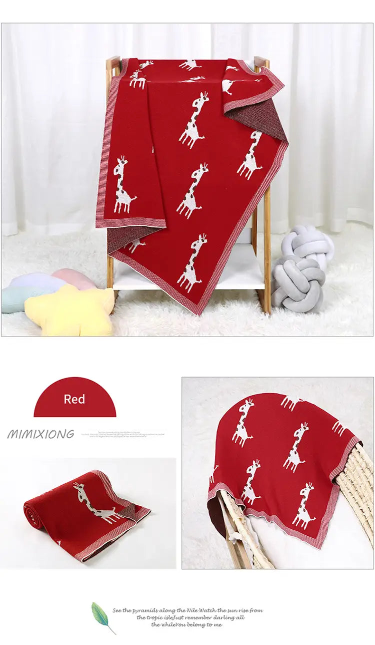 Rote gestrickte Baumwoll-Babytdecke mit weißen Giraffenmustern und einer kontrastierenden dunkelfarbigen Bordüre.