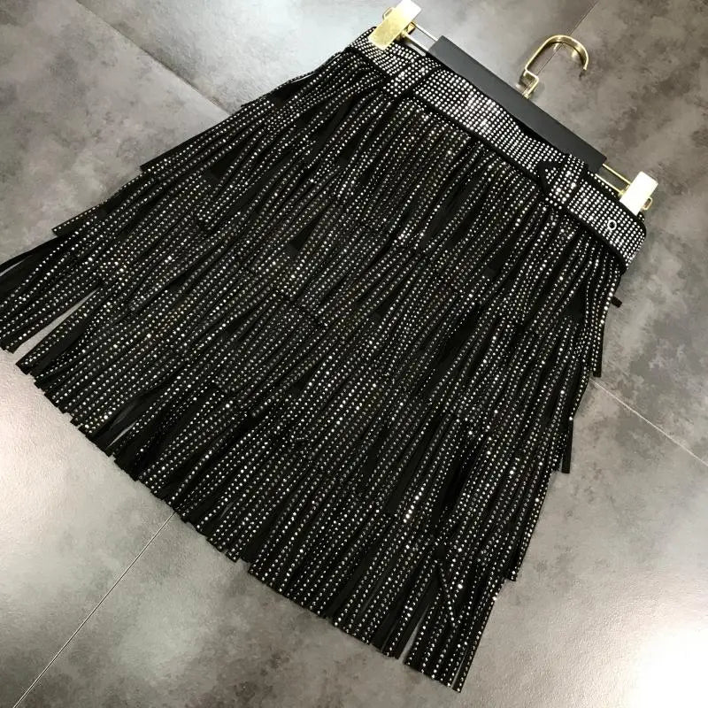 Mini-jupe noire à franges taille haute, agrémentée de strass scintillants le long de la ceinture et descendant en cascade sur chaque frange.