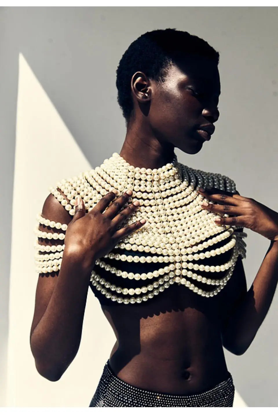 Un collier de mode en chaîne corporelle de perles d’un blanc cassé saisissant, avec un corsage orné de perles, et des rangées superposées de perles formant un design structuré à col haut.