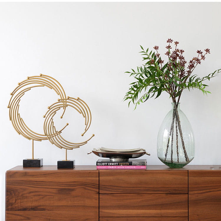 Gold-toned abstract circular metal sculpture with black marble bases designed as office desk decor.