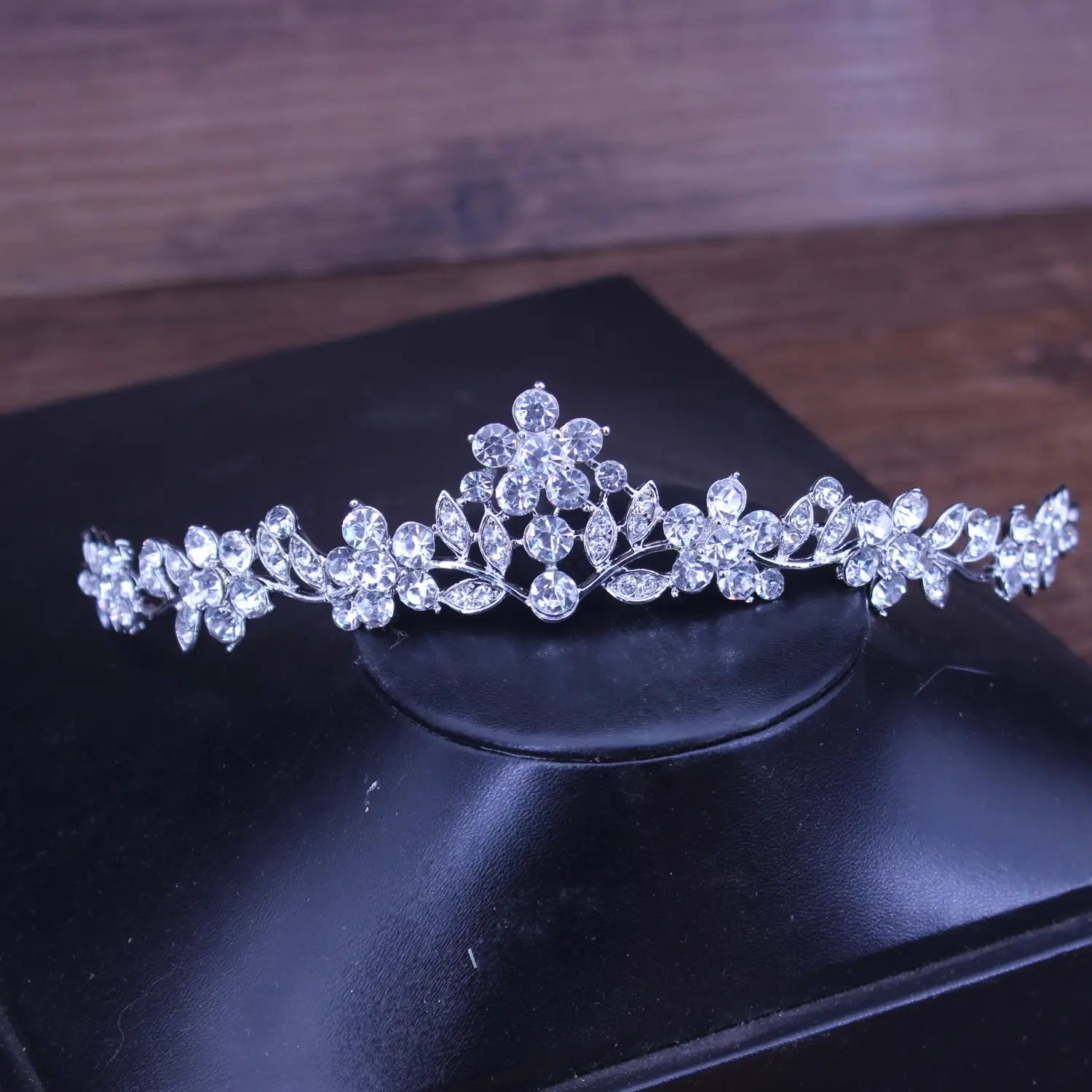 Una diadema de boda floral con tiara de novia de cristal plateado brillante, adornada con flores y hojas de cristal transparentes.
