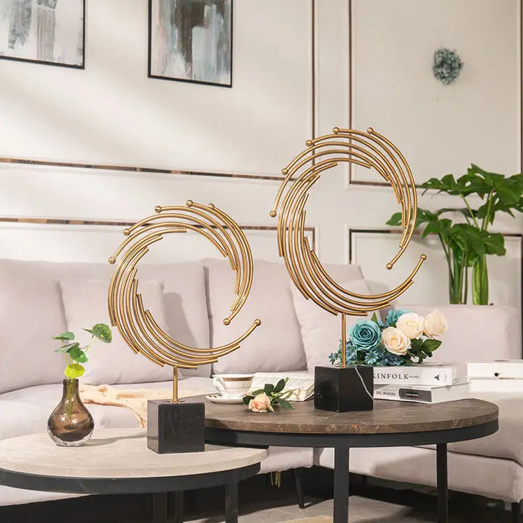 Gold metal abstract sculpture with gold-toned concentric circular designs mounted on a sleek black marble base ideal for office desk decor.