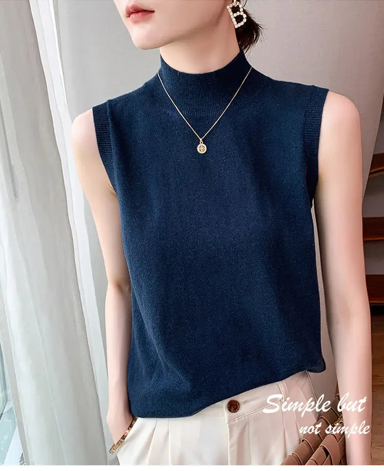 A navy blue wool turtleneck sleeveless sweater vest with a high neckline and ribbed edges.